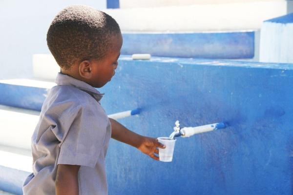 Haitilainen poika juo vettä Planin avulla rakennetusta vesipisteestä.