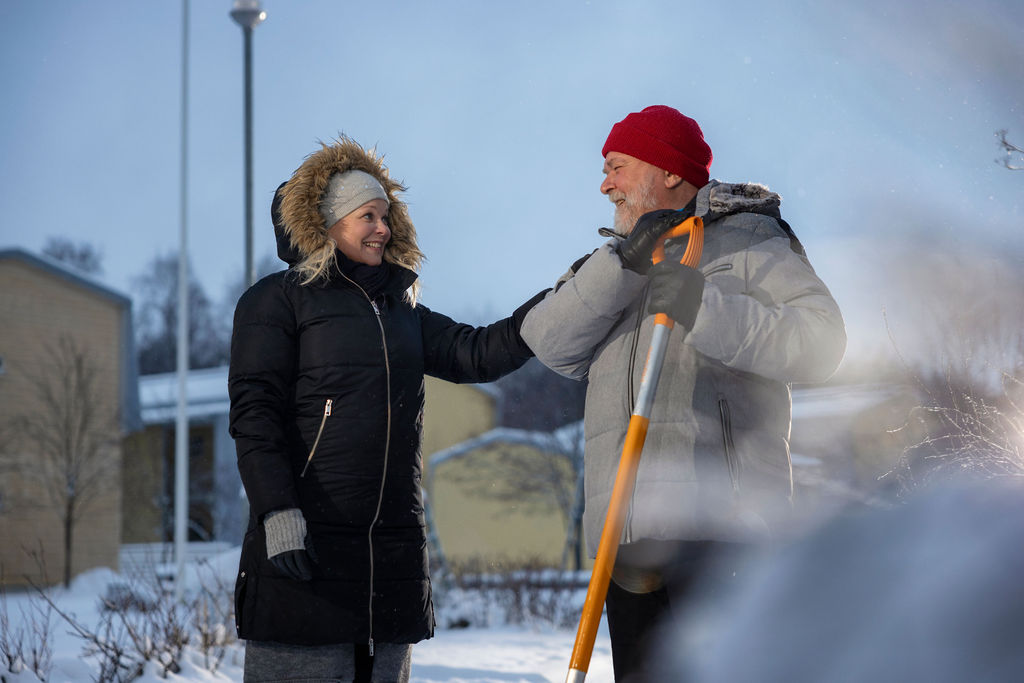 Kuvassa nainen pitää kättään ikäihmisen olkapäällä osoittaen tukea.