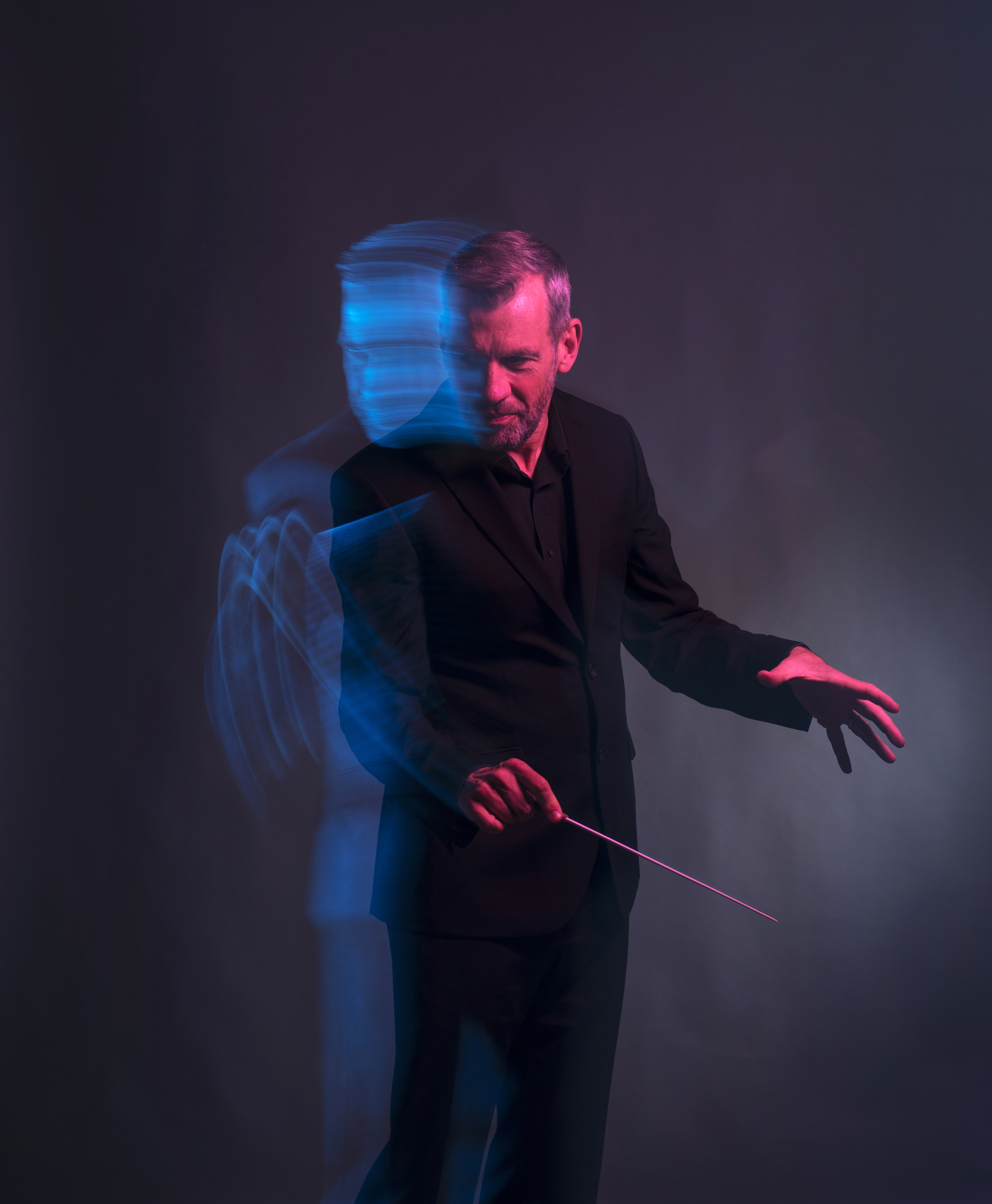 Mies seisoo kädessään kapelimastarin tikku.