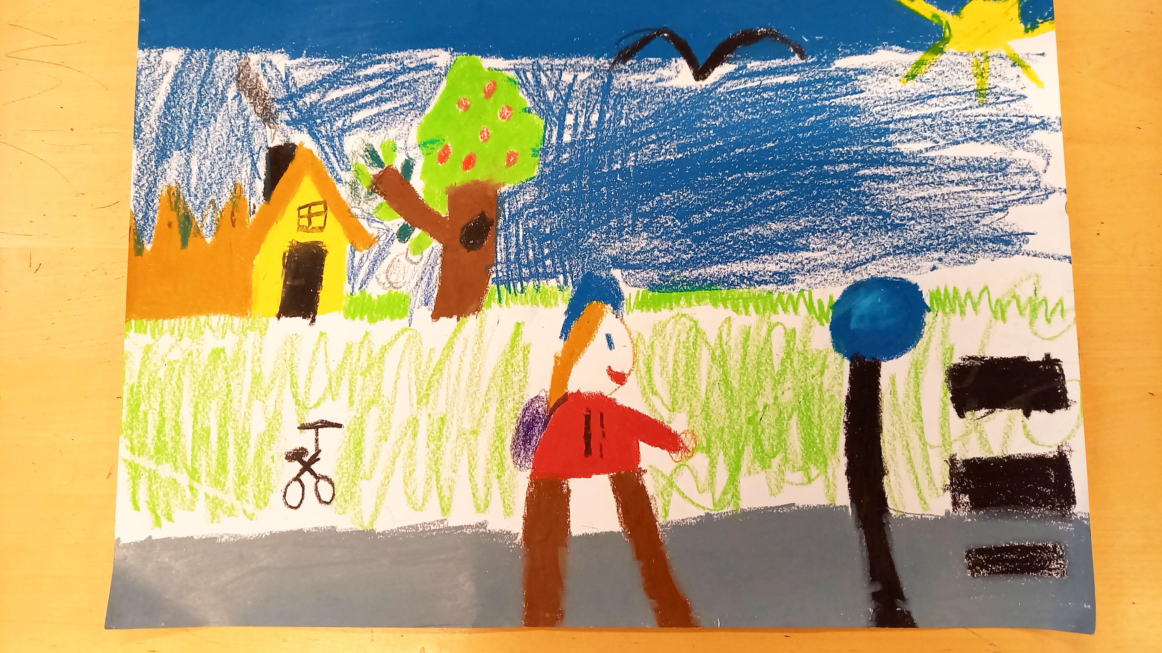 Lapsen piirustus, jossa keltainen talo, hedelmää ja jalankulkija.