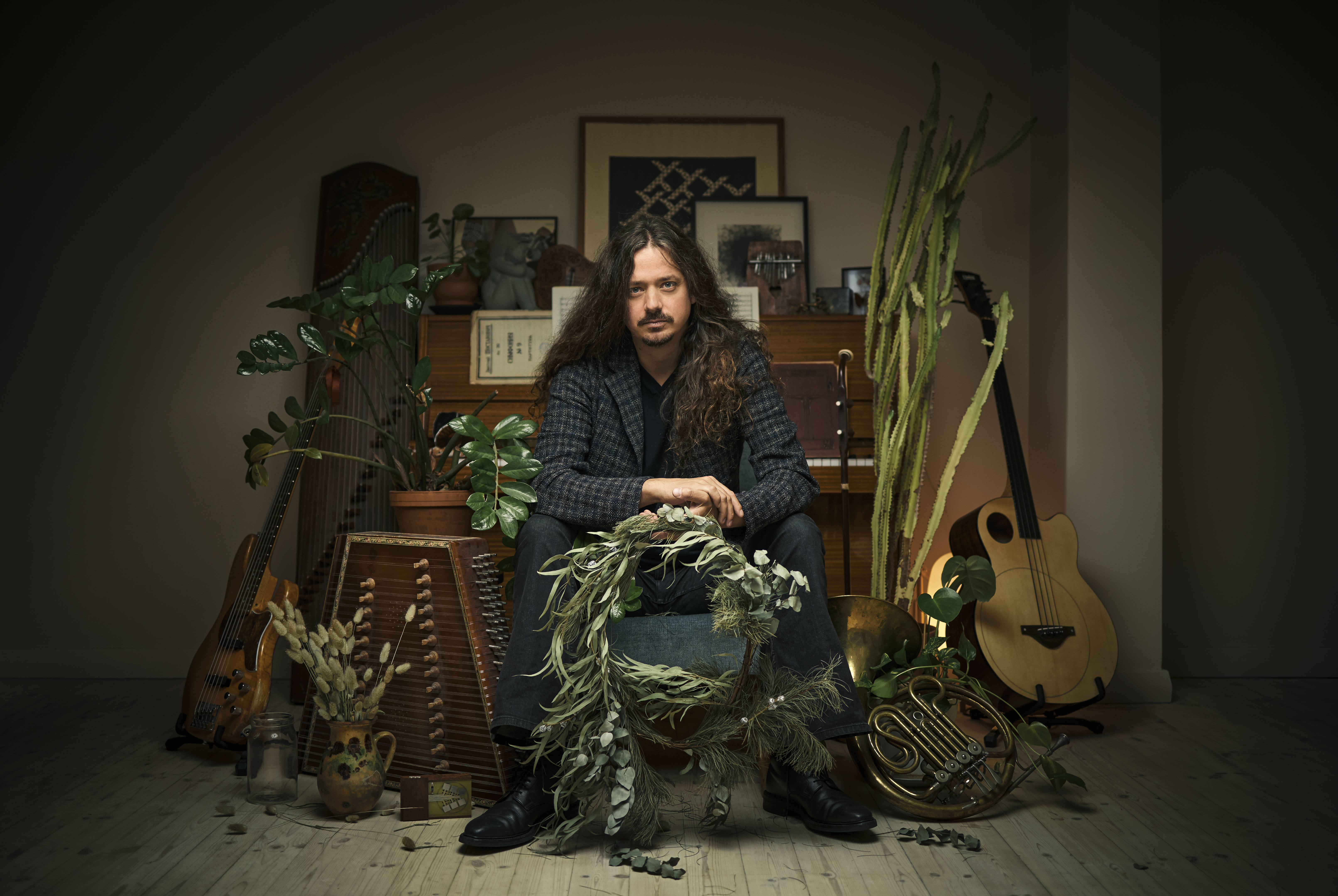 Lauri Porra istuu huonekasvien ja soittimien seassa.