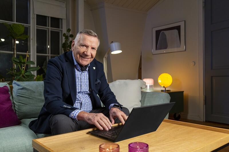 Mies hymyilee tietokoneen äärellä.