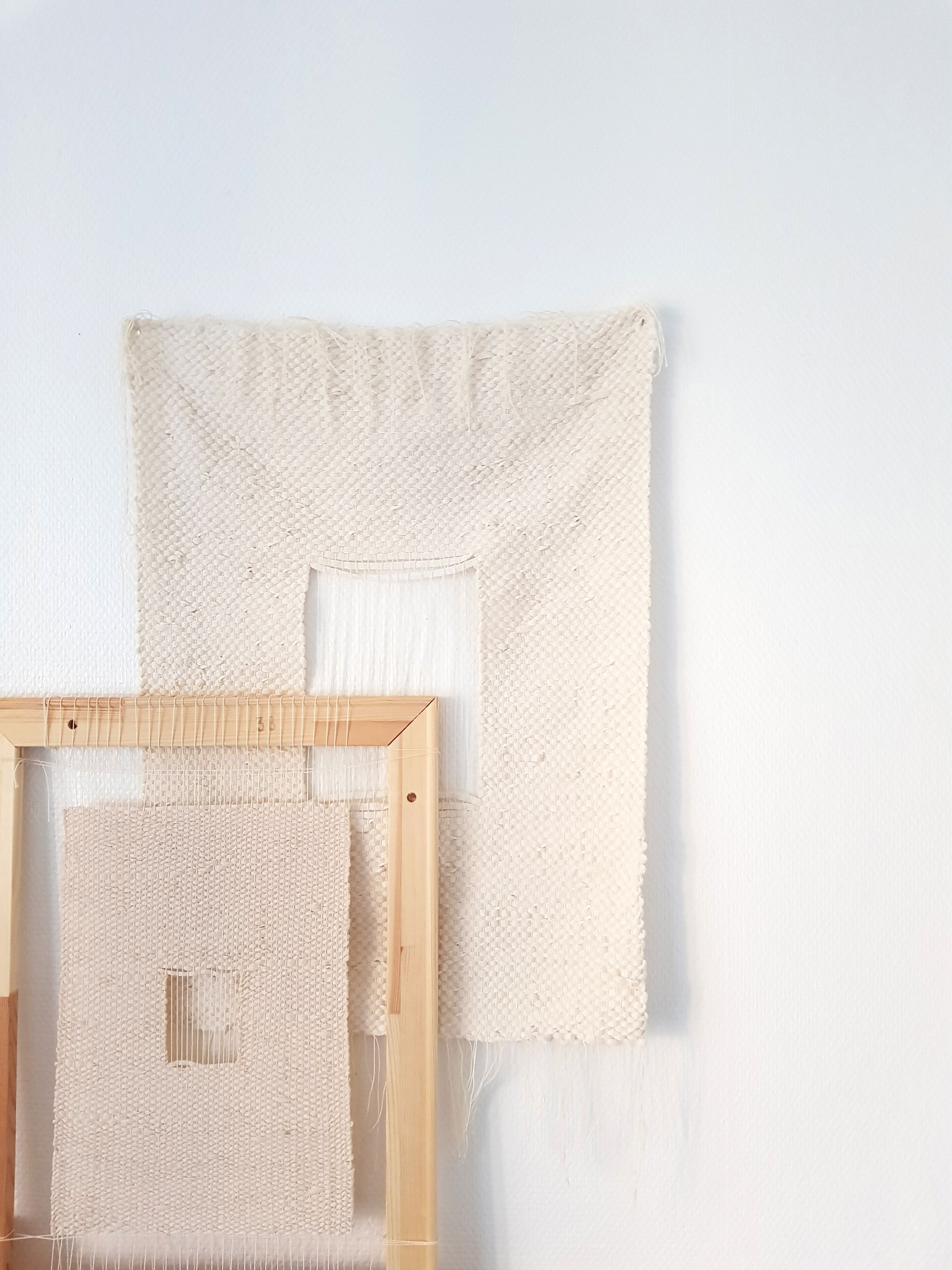 Kaksi vaaleaa tesktiilistä kudottua neliötä, toinen kehystetty.