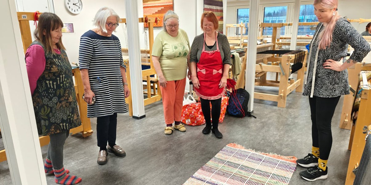 Kutojia vastavalmistuneen maton äärellä.