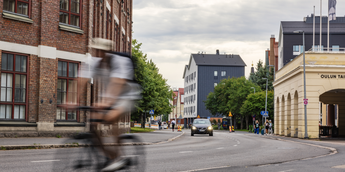 Mies pyöräilee keskustassa.