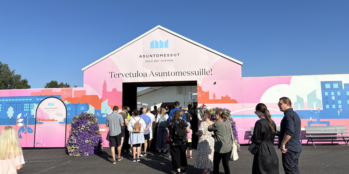 Ihmisiä jonossa vaaleanpunaisella portilla. Portissa lukee: Tervetuloa Asuntomessuille!