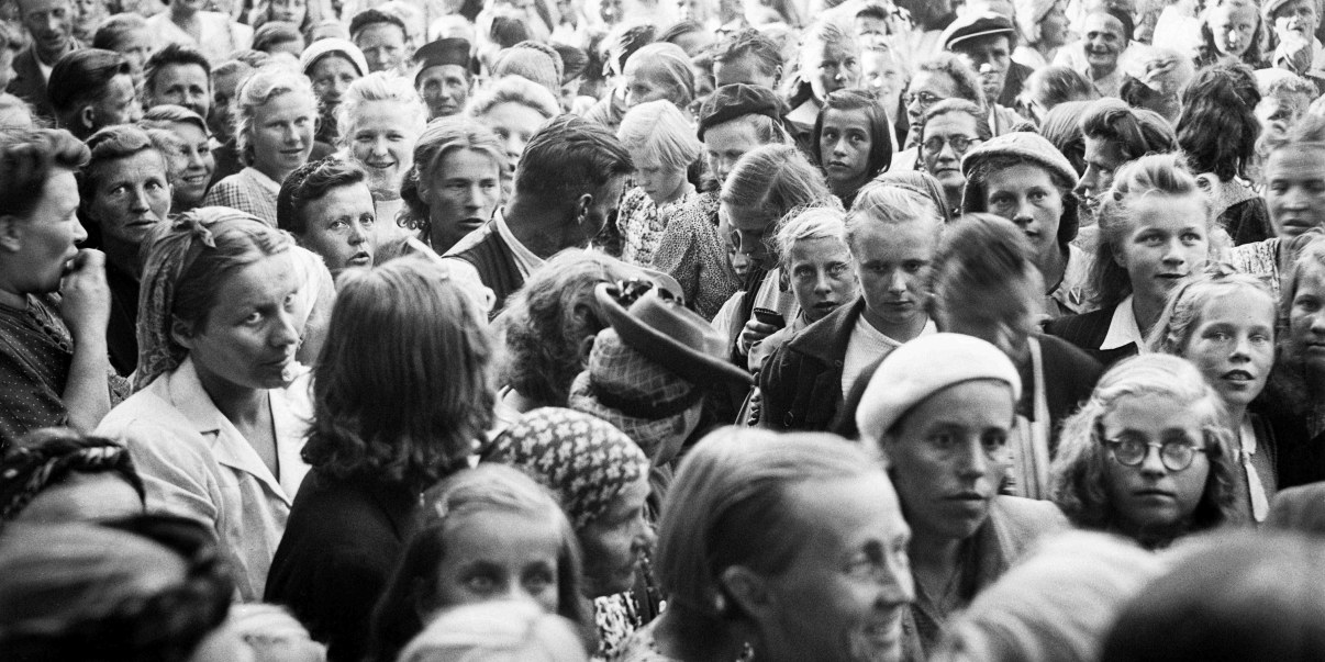 Vaihtoehtoinen teksti: Mustavalkoinen kuva isosta joukosta henkilöitä, kuvattu ylhäältä päiden päältä.