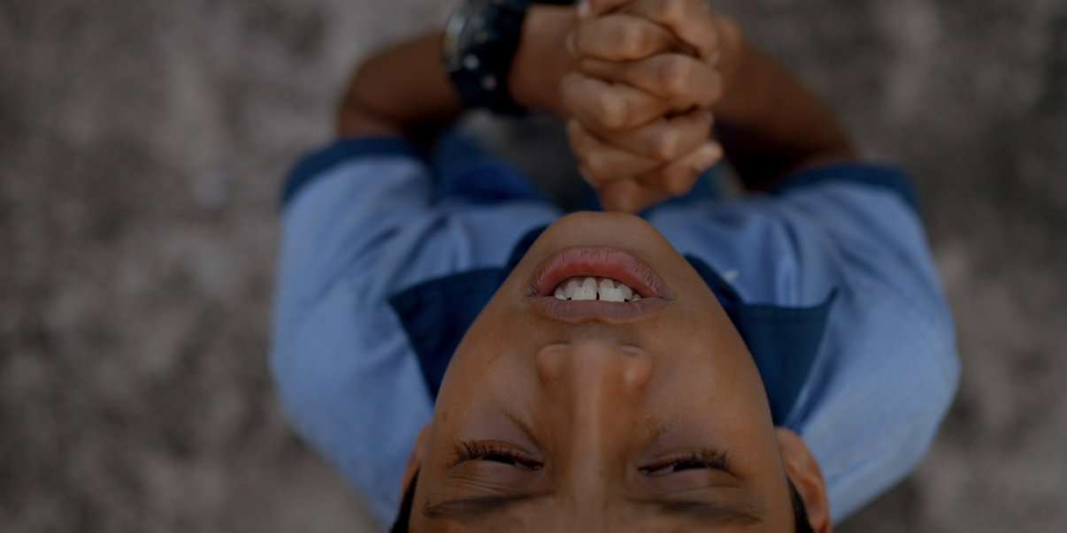 kuvassa on rukoileva poika kuva on otettu ylhäältä päin