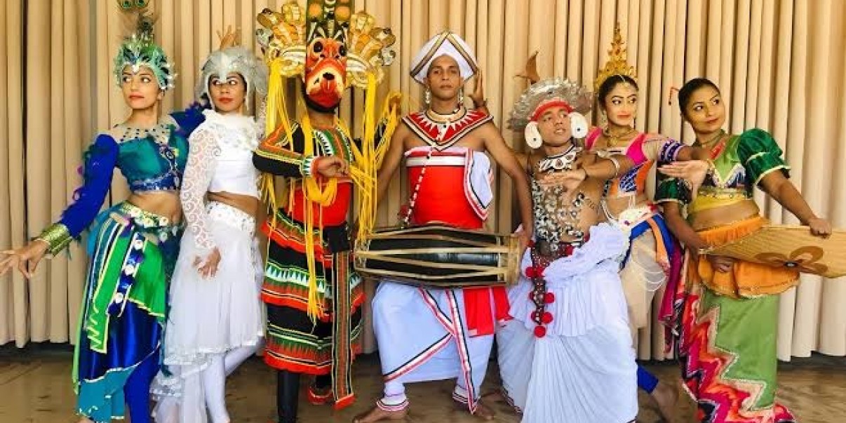 Six Sri lankan people standing wearing their national costumes