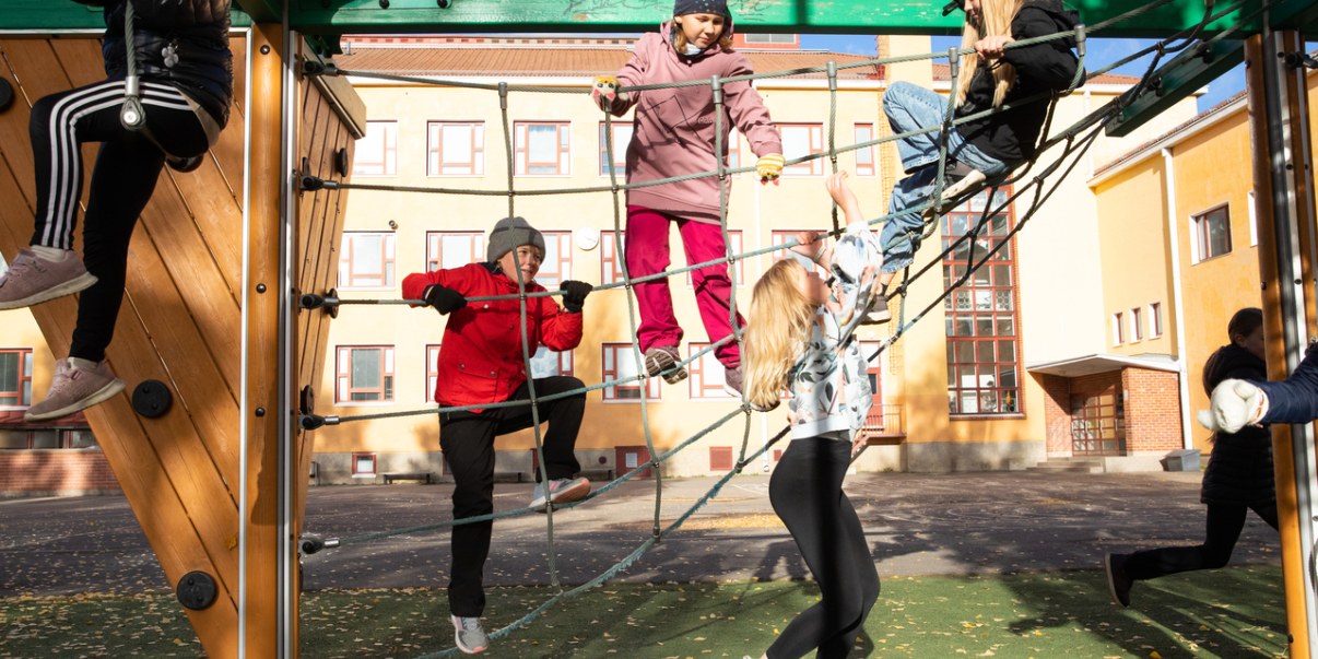 Koululaiset leikkimässä välitunnilla kiipeilytelineessä. 