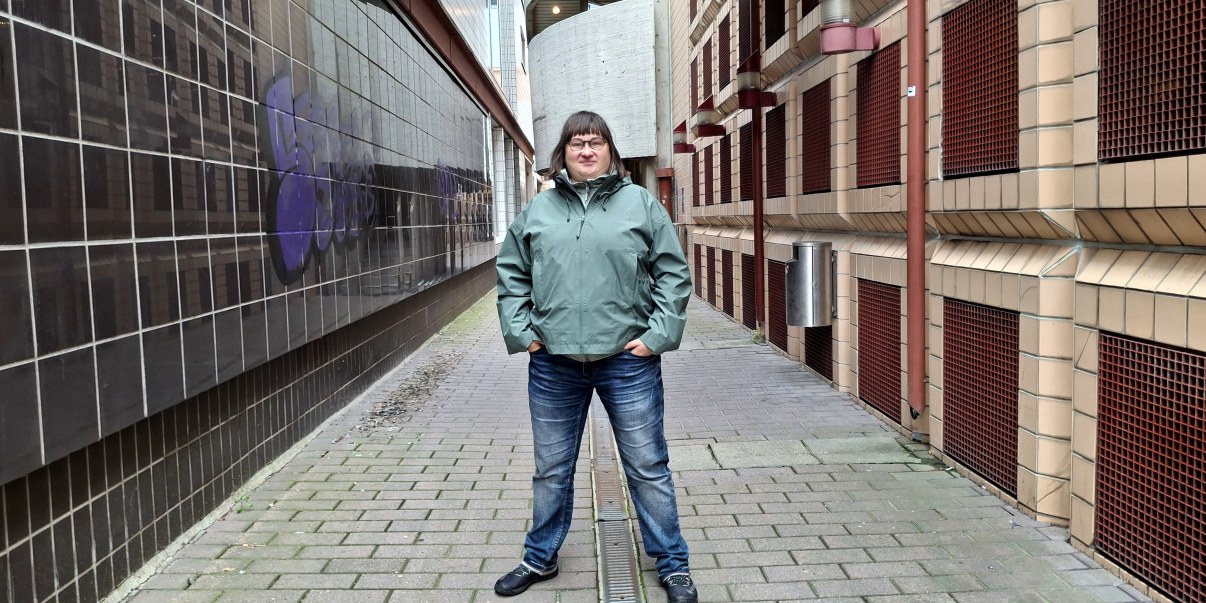 Vihreätakkinen nainen seisoo käytävällä