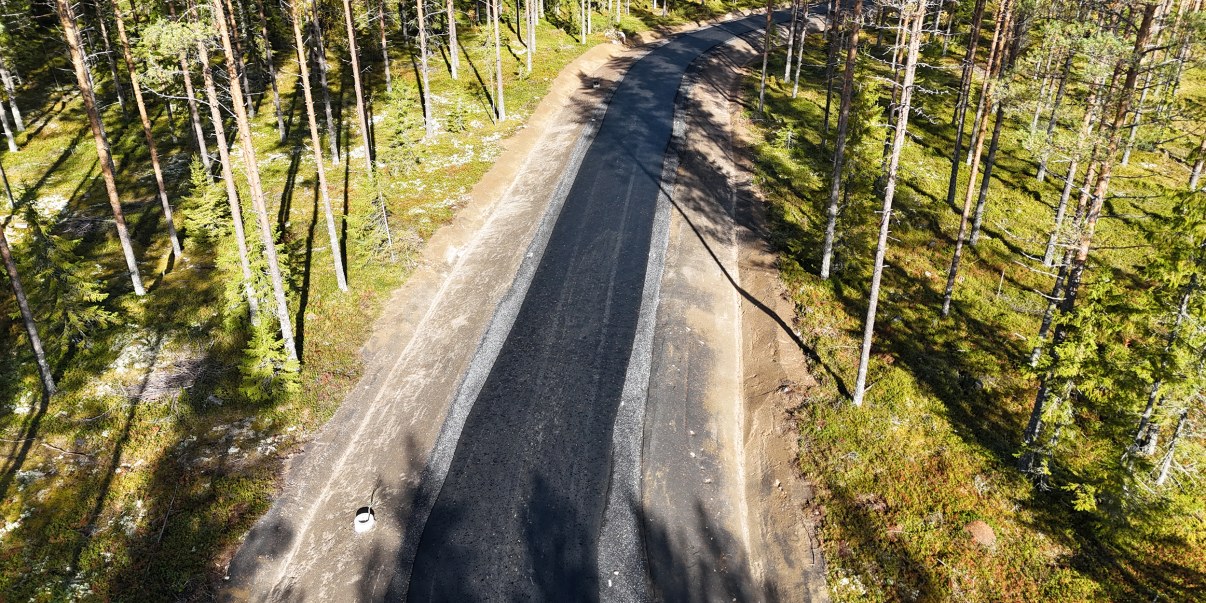 Kuvassa asfaltoitu rullarata ylhäältäpäin kuvattuna aurinkoisena päivänä. Ympärillä metsää.