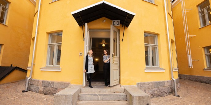 Oulun Lyseon lukion päärakennuksen ovella kaksi opettajaa 