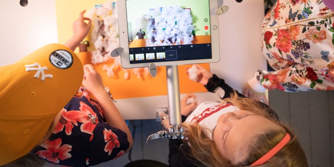kolme lasta ja iPad ylhäältäpäin kuvattuna. Lapset tekemässä animaatiota.