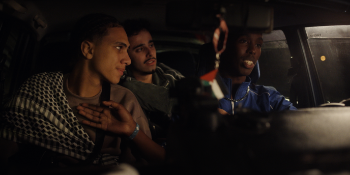 Kuvassa kolme nuorta autossa