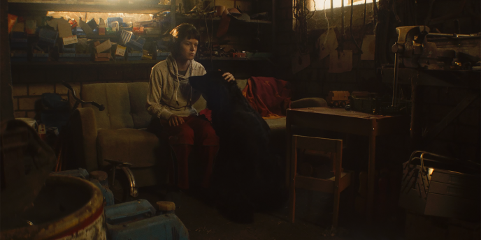 istuva henkilö koiran kanssa hämyisessä huoneessa