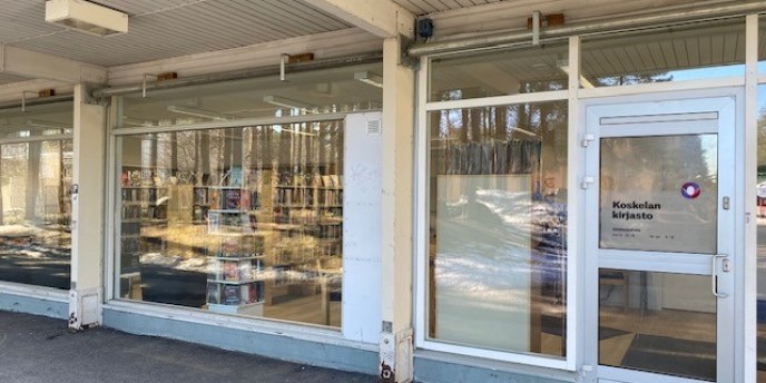 Lasiseinä, jossa ovi, ovessa teksti Koskelan kirjasto.