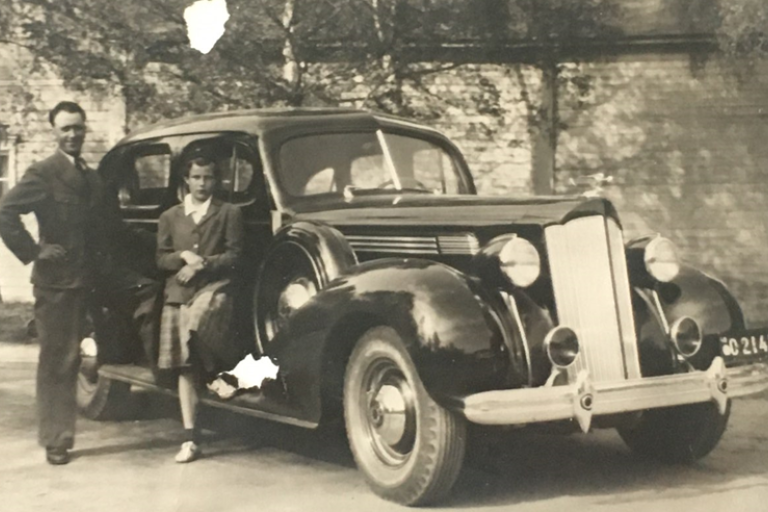 Mies ja tyttö seisovat mustan auton vieressä.