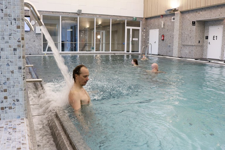 Yksi uimari hierovan vesisuihkun alla muita uimassa