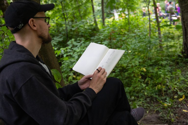 Henkilö kirjoittaa runoa vihkoonsa