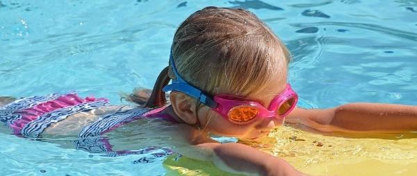 Kuvassa on esiopetusikäinen tyttö uimassa uimahallissa.