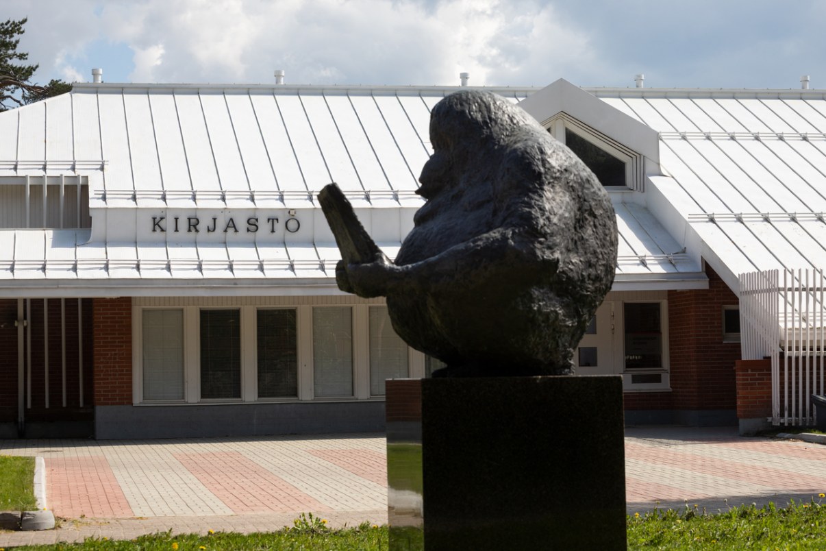 Brown-brick building. In the front of the photo, a statue of an orangutan reading a book.
