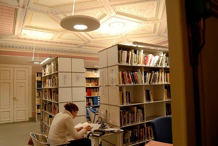 Kirjahyllyjä ja ihminen lukemassa.