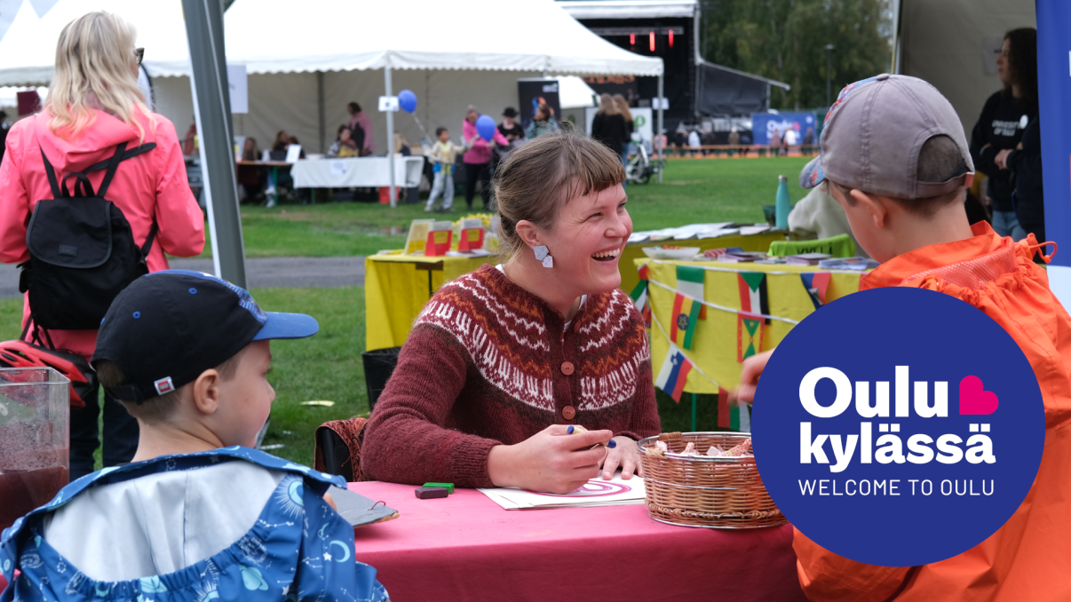 Oulu kylässä -festivaalin esittelypiste, kuvan päällä logo