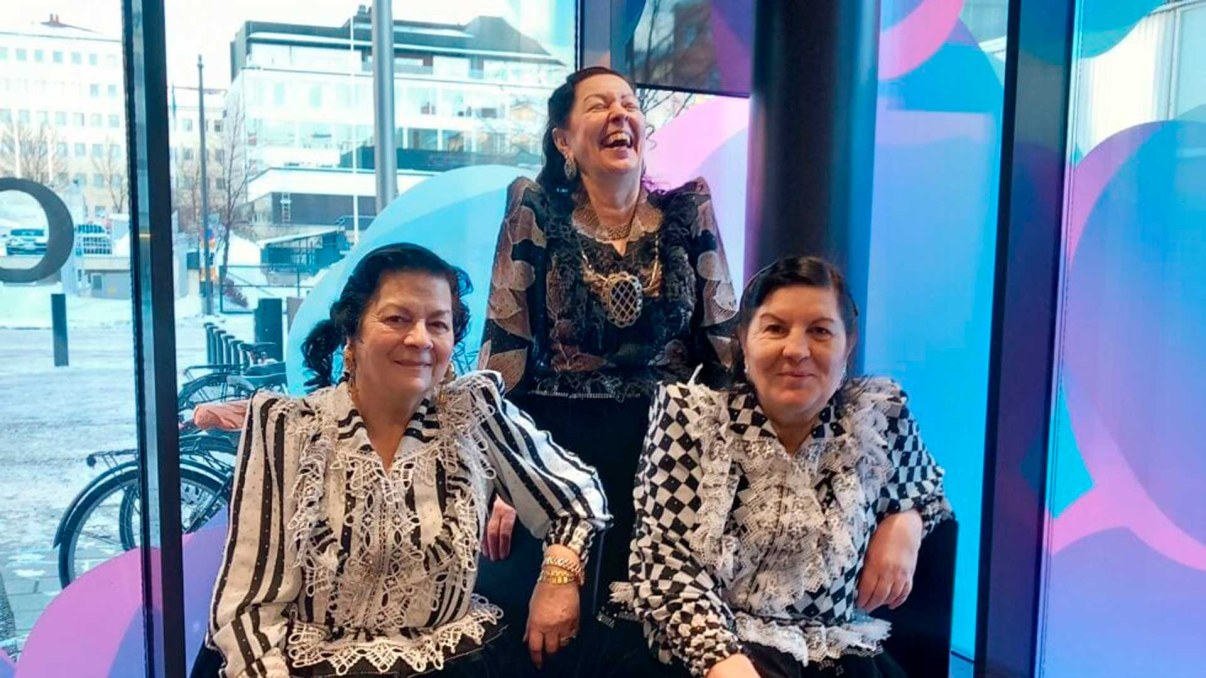 Three women in Roman outfits smiling. 