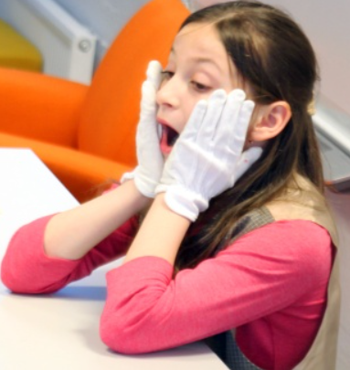 kuvassa lapsi jolla on valkoist käsineet pitelee postiaan suu auki, kuva rajattu keskivartalosta ylöspäin