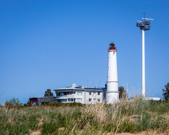 punavalkoinen majakka puiden ympäröimänä
