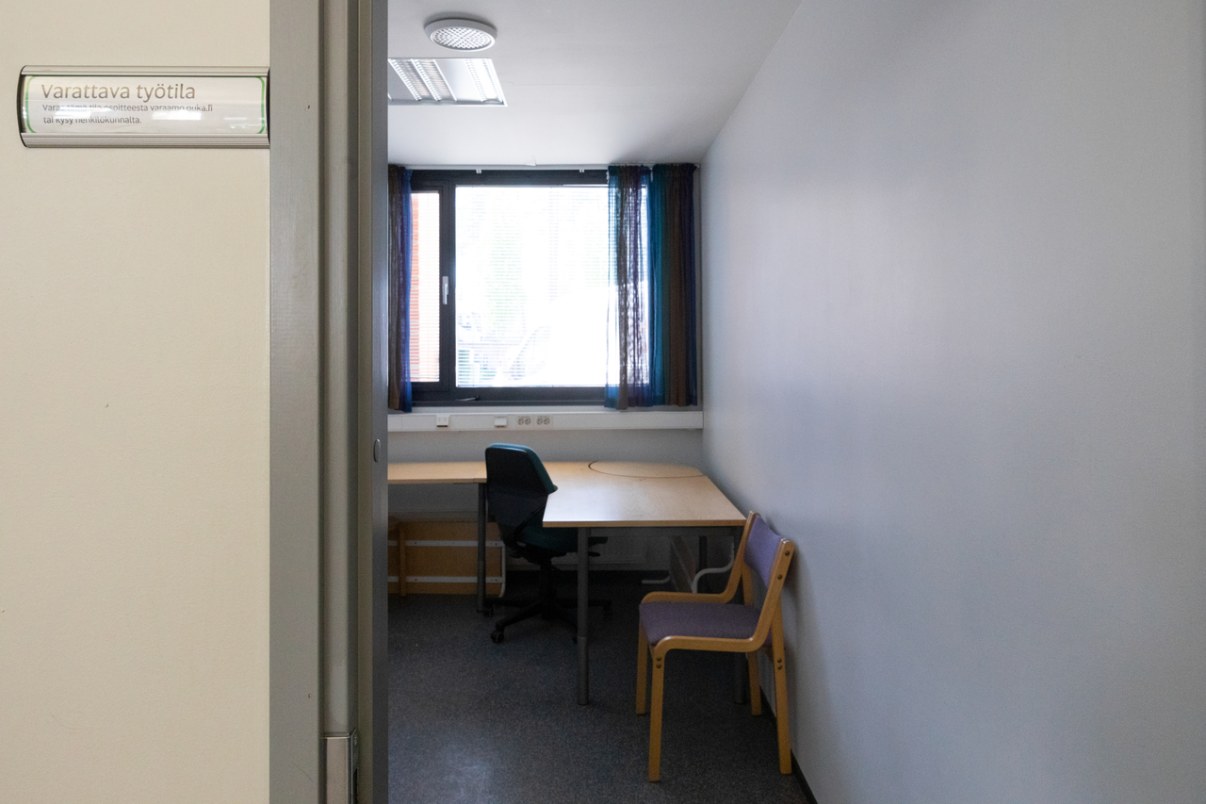 Näkymä työtilaan jossa työpöytä ja kaksi tuolia.