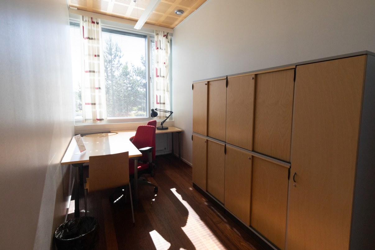 Työtila jossa työpöytä, kaksi tuolia ja kaapisto.