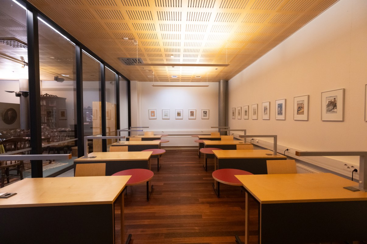 Tila jossa yksi lasiseinä ja useita työpöytiä.