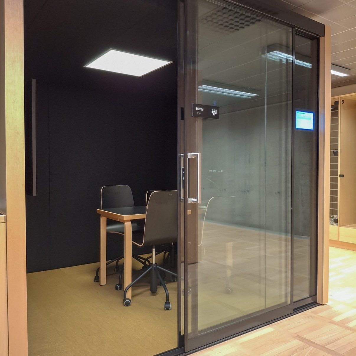 Työskentelytila jossa suuret lasiovet, pöydän ympärillä neljä tuolia.