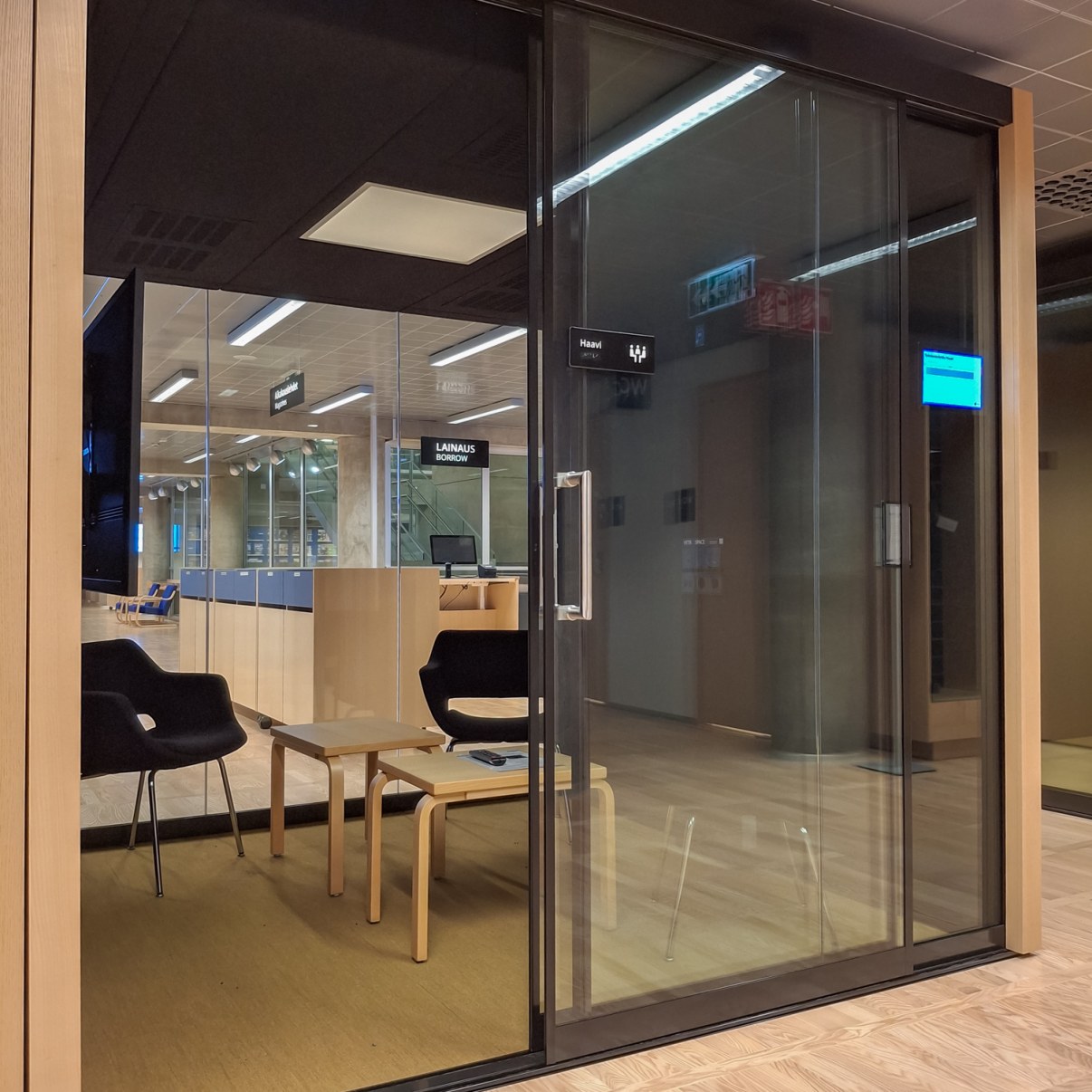 Lasiseinäinen työskentelytila jossa on kaksi tuolia ja kaksi pientä pöytää.