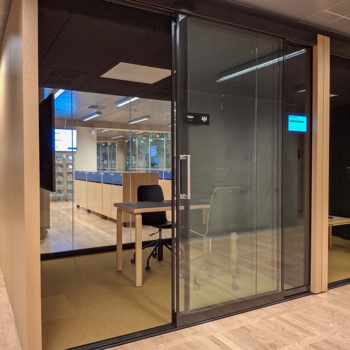 Lasiseinäinen työskentelytila jossa on pöydän ympärillä kaksi tuolia.