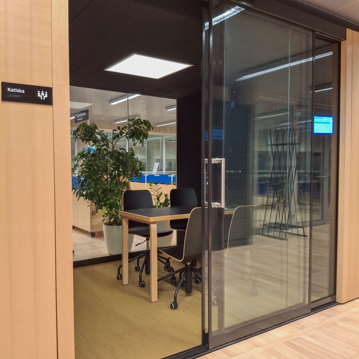 Lasiseinäinen työskentelytila jossa on pöydän ympärillä neljä tuolia.