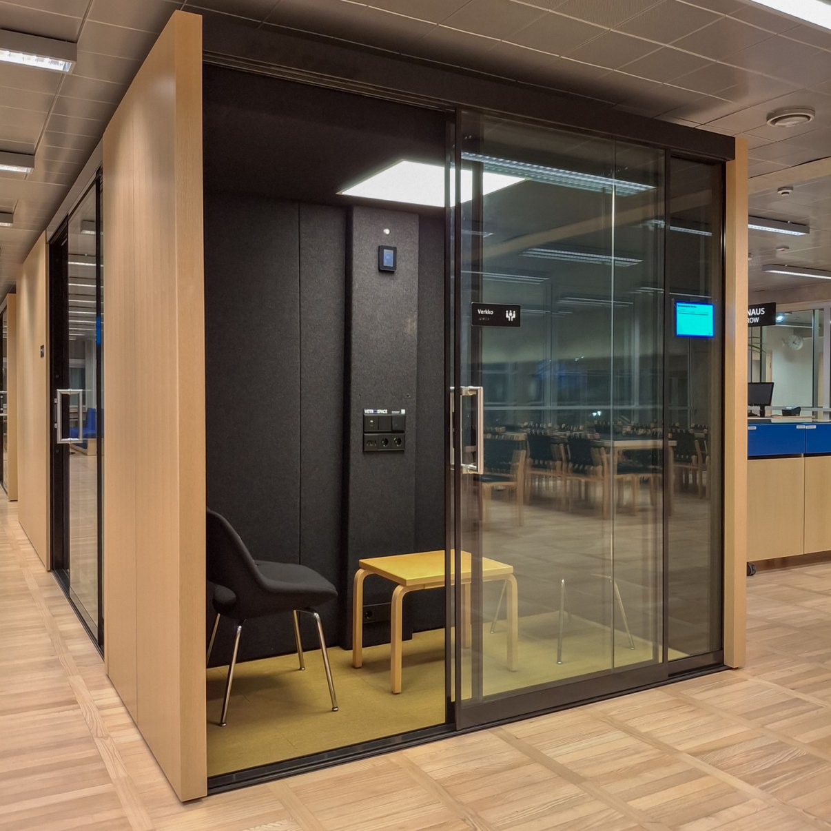 Pieni työskentelytila jossa suuret lasiovet, tilassa on kaksi tuolia ja pieni pöytä.