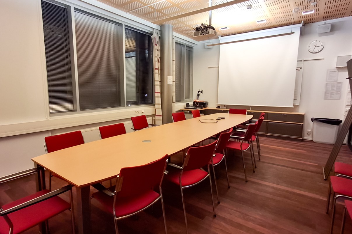 Neuvotteluhuone, jossa pitkä pöytä, jonka ympärillä tuoleja.