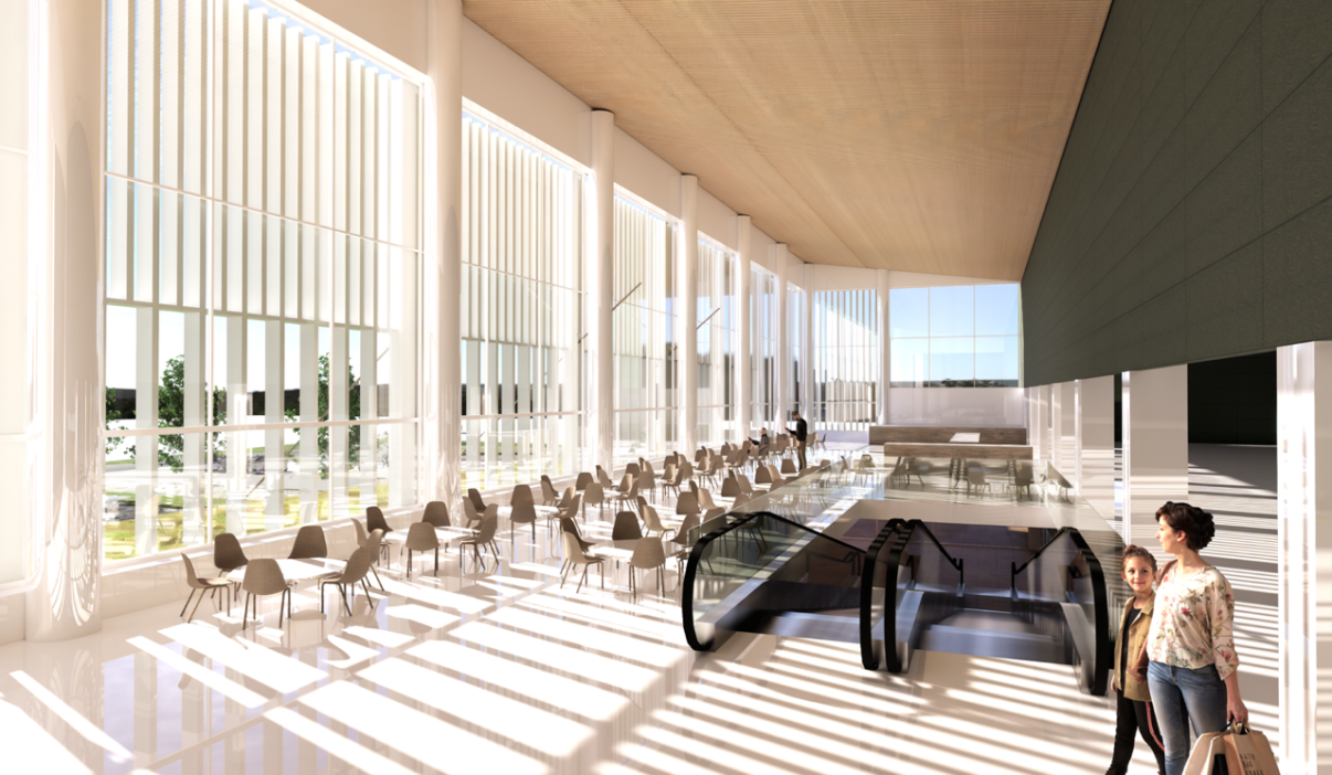 Suuret ikkunat, joista aurinko paistaa kahvilamaiseen tilaan. Liukukäytävä tulee tilaan alhaalta päin.