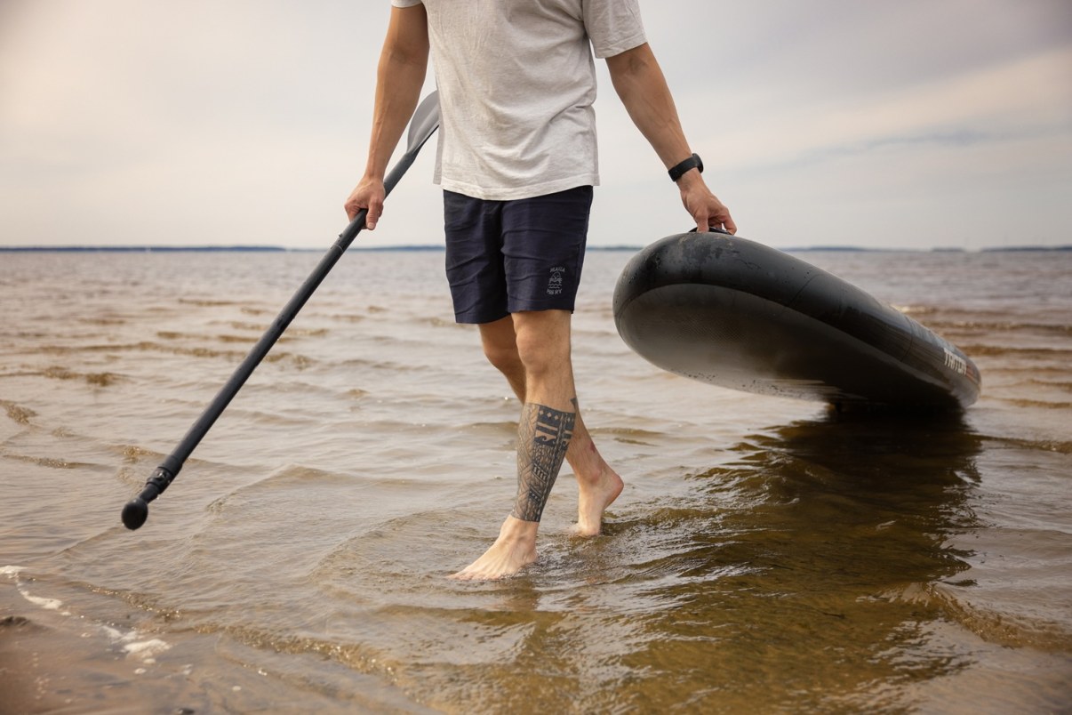 Mies kantaa sup-lautaa pois merestä. 