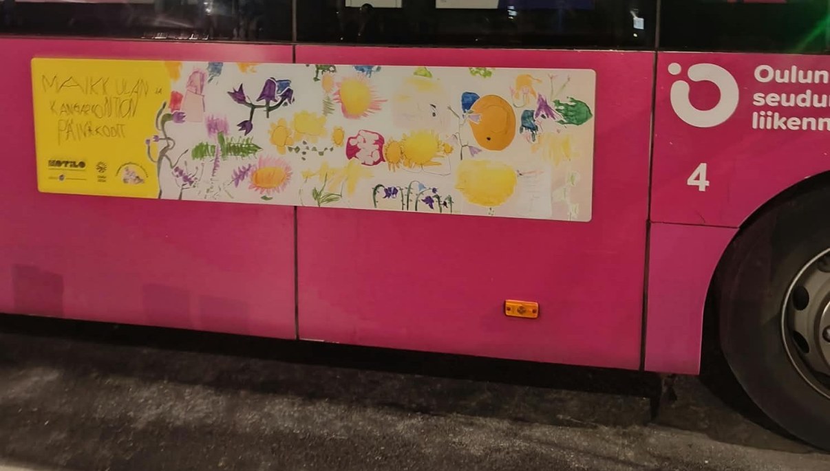Bussin kylkeen tarroitettu lasten taideteos, jossa on paljon värikkäitä kukkia.