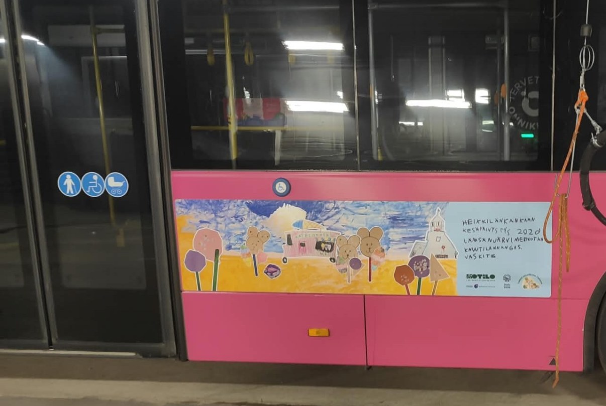 Bussin kylkeen tarroitettu lasten taidedetos rantamaisemasta. 