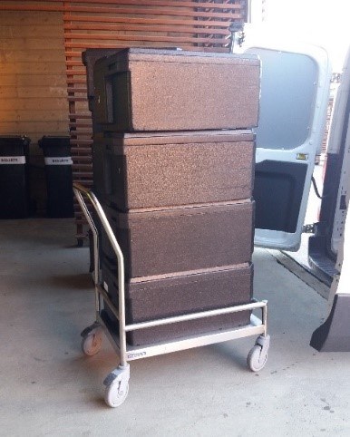 Mustia elintarvikkeiden kuljetuslaatikoita kärryssä lastauslaiturilla.