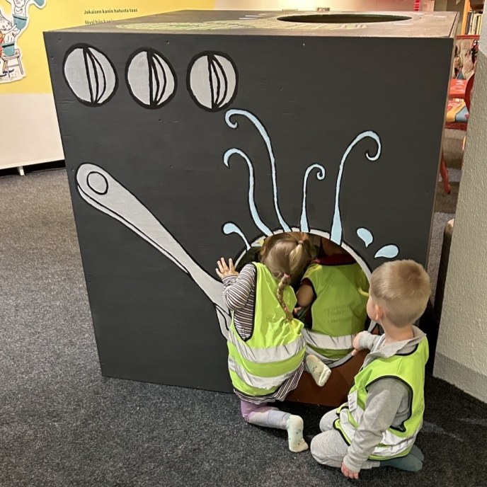 kuvassa lapset kurkkivat sisälle mentävään lootamaiseen rakenteeseen