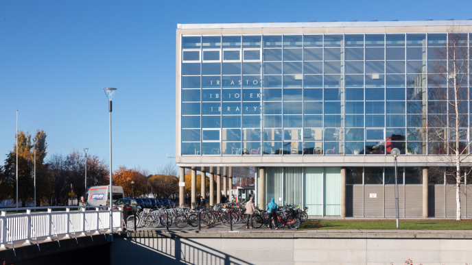 A concrete building with a glass façade. A colonnade in the front.