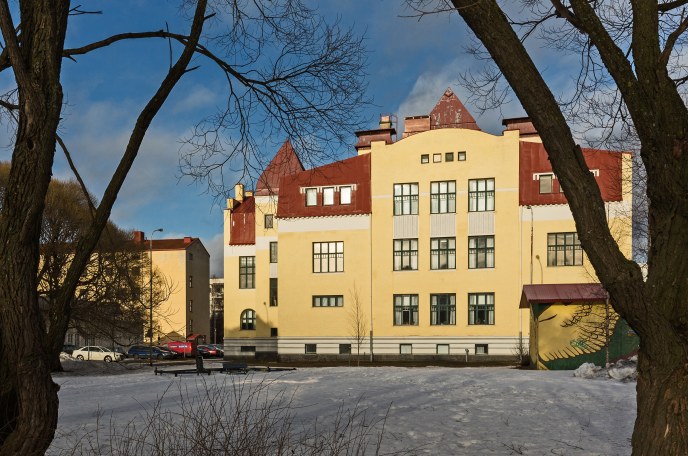 Kuva keltainen koulurakennus ilta-auringossa