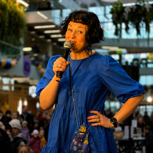 A woman in a blue dress speaking to a microphone