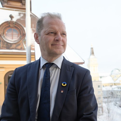 Kaupunginjohtaja Ari Alatossava katsoo ohi kameran, taustalla kaupungin talo